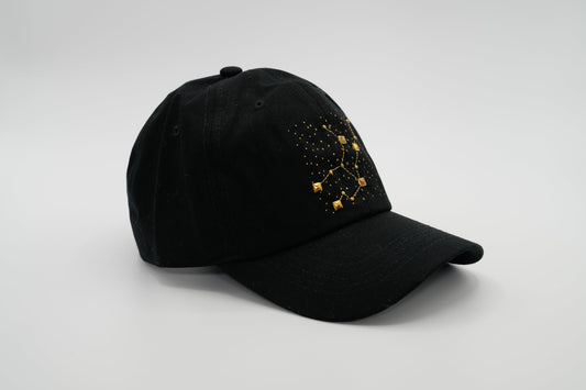 A black baseball cap with the Virgo zodiac sign embroidered and riveted in gold on the front.